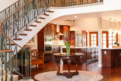 Kitchen - large transitional medium tone wood floor and brown floor kitchen idea in Orange County with a double-bowl sink, raised-panel cabinets, brown cabinets, quartzite countertops, white backsplash, stone tile backsplash, stainless steel appliances and two islands