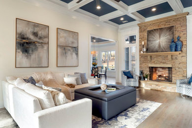 Ejemplo de sala de estar abierta clásica renovada grande con paredes beige, suelo de madera en tonos medios, todas las chimeneas, marco de chimenea de piedra, televisor colgado en la pared, suelo gris y casetón