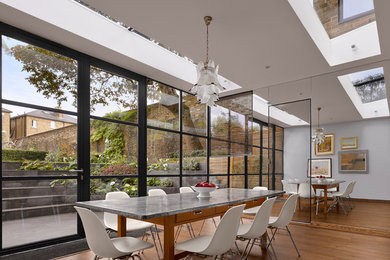 Photo of a contemporary dining room in London with grey walls and medium hardwood flooring.