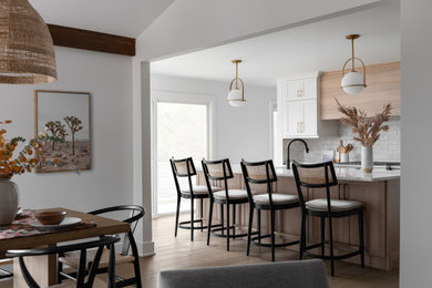 Example of a large danish l-shaped light wood floor eat-in kitchen design in Detroit with an undermount sink, shaker cabinets, white cabinets, quartz countertops, white backsplash, subway tile backsplash, stainless steel appliances, an island and white countertops