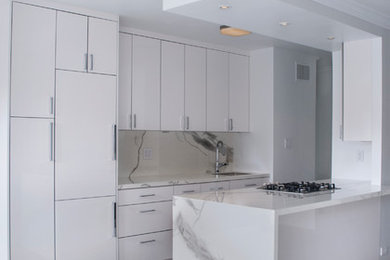 Eat-in kitchen - mid-sized modern eat-in kitchen idea in New York with white cabinets, white backsplash and white countertops