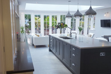 This is an example of a large traditional single-wall eat-in kitchen in Surrey with a double-bowl sink, shaker cabinets, grey cabinets, quartzite benchtops, grey splashback, mirror splashback, stainless steel appliances, limestone floors, with island and grey floor.