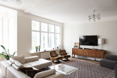 Mittelgroßes, Offenes Modernes Wohnzimmer mit grauer Wandfarbe, braunem Holzboden und braunem Boden in Berlin