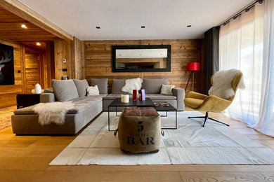 Aménagement d'un salon montagne en bois de taille moyenne et ouvert avec un mur beige, parquet clair, cheminée suspendue, un téléviseur fixé au mur, un sol beige et un plafond en bois.