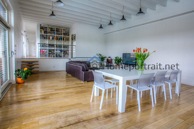 Cette image montre une salle à manger design avec un mur blanc, parquet clair, un sol beige et poutres apparentes.