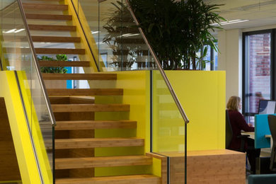 Imagen de escalera recta actual de tamaño medio con escalones de madera, contrahuellas de vidrio y barandilla de metal