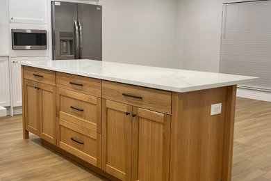 Example of a mid-sized trendy l-shaped porcelain tile and brown floor open concept kitchen design in Orlando with an undermount sink, shaker cabinets, light wood cabinets, quartz countertops, white backsplash, quartz backsplash, stainless steel appliances, an island and white countertops