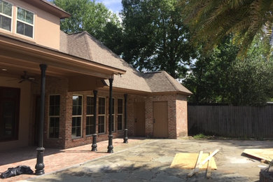 Example of a large trendy backyard stone patio kitchen design in New Orleans with a roof extension