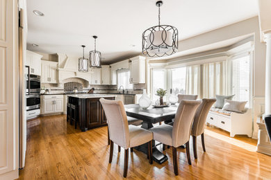 Inspiration for a large timeless u-shaped brown floor and medium tone wood floor eat-in kitchen remodel in Chicago with an undermount sink, raised-panel cabinets, white cabinets, quartz countertops, multicolored backsplash, mosaic tile backsplash, stainless steel appliances, an island and multicolored countertops