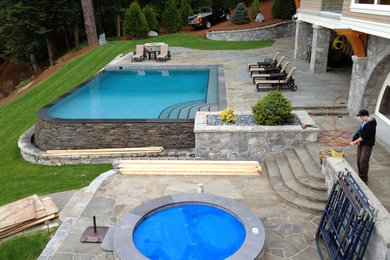 Hot tub - large transitional backyard stone and rectangular infinity hot tub idea in Vancouver