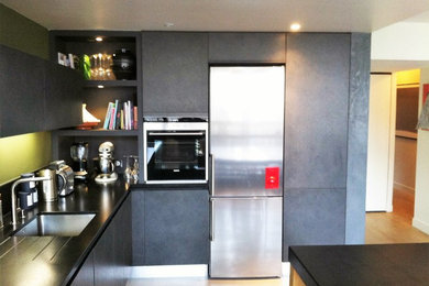 Expansive contemporary single-wall open plan kitchen in Paris with a single-bowl sink, flat-panel cabinets, dark wood cabinets, granite benchtops, black splashback, stainless steel appliances, concrete floors and no island.