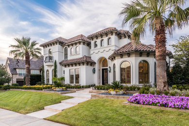 Inspiration for a large mediterranean two-storey stucco beige house exterior in Dallas with a hip roof and a tile roof.