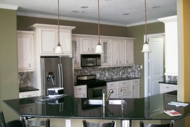 Example of a minimalist l-shaped kitchen pantry design in Houston with an undermount sink, raised-panel cabinets, white cabinets, marble countertops, stainless steel appliances and an island