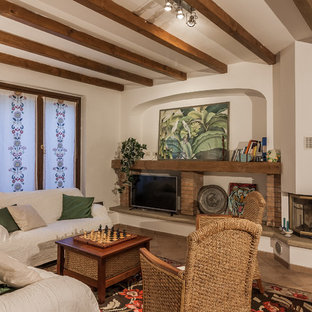 Inspiration for a mediterranean enclosed living room in Other with white walls, a standard fireplace, a freestanding tv and brown floors.