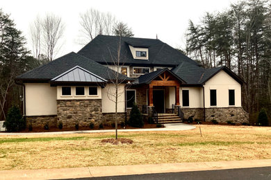 French country stucco house exterior idea in Charlotte with a hip roof and a metal roof