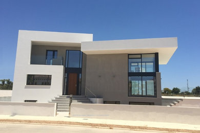 Imagen de fachada de casa blanca contemporánea grande de tres plantas con revestimiento de estuco, tejado plano y tejado de varios materiales