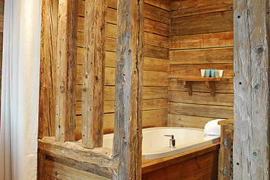 Inspiration pour une salle de bain chalet en bois de taille moyenne avec un bain bouillonnant, parquet clair, un plan de toilette en bois, meuble simple vasque, un plafond en bois, poutres apparentes et boiseries.