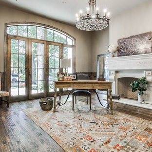 Imagen de despacho mediterráneo, grande, con suelo de madera oscura, chimenea tradicional, marco de chimenea de piedra y escritorio independiente