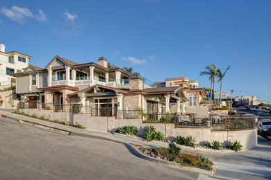 This is an example of a large beach style split-level grey house exterior in Orange County with mixed siding, a green roof and a gable roof.