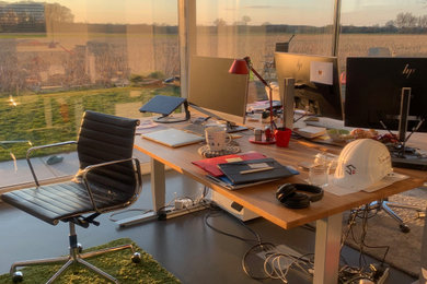 Großes Modernes Arbeitszimmer mit Arbeitsplatz, weißer Wandfarbe, Betonboden, freistehendem Schreibtisch und grauem Boden in Sonstige