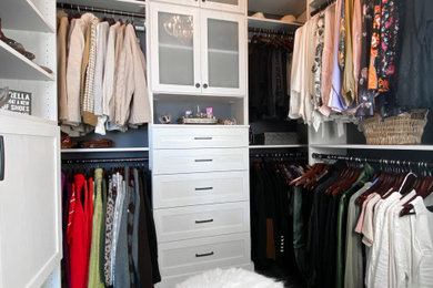 Example of a mid-sized walk-in closet design in Burlington with shaker cabinets and light wood cabinets