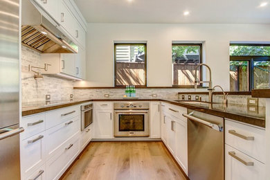 This is an example of a modern u-shaped eat-in kitchen in San Francisco with an undermount sink, shaker cabinets, white cabinets, terrazzo benchtops, white splashback, matchstick tile splashback, stainless steel appliances, dark hardwood floors, a peninsula and beige floor.