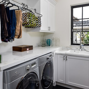マイアミの小さいトランジショナルスタイルのおしゃれな洗濯室 (ドロップインシンク、シェーカースタイル扉のキャビネット、白いキャビネット、大理石カウンター、白い壁、左右配置の洗濯機・乾燥機、濃色無垢フローリング、茶色い床、白いキッチンカウンター) の写真