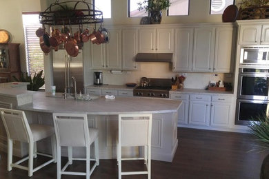 Example of a large classic galley dark wood floor and blue floor open concept kitchen design in Phoenix with raised-panel cabinets, white cabinets, quartzite countertops, white backsplash, subway tile backsplash, stainless steel appliances, an island and an undermount sink