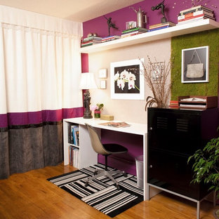 Exempel på ett mellanstort eklektiskt hemmabibliotek, med mellanmörkt trägolv, ett fristående skrivbord och lila väggar