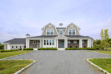Example of a beach style beige two-story wood house exterior design in Providence with a gambrel roof and a shingle roof