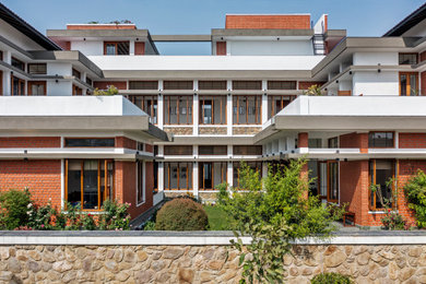 Large trendy multicolored two-story brick house exterior photo in Delhi with a hip roof and a mixed material roof