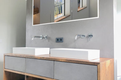 Kleines Modernes Badezimmer mit flächenbündigen Schrankfronten, Schränken im Used-Look, Waschtisch aus Holz, brauner Waschtischplatte, Doppelwaschbecken und schwebendem Waschtisch in München