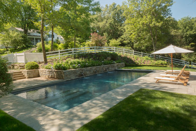 Photo of a mid-sized traditional backyard rectangular pool in New York with a water feature.