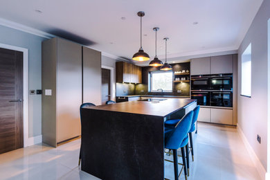 Foto de cocinas en L moderna de tamaño medio abierta con electrodomésticos de acero inoxidable y una isla