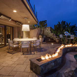 На фото: большой дворик на заднем дворе в морском стиле с местом для костра, навесом и мощением тротуарной плиткой с