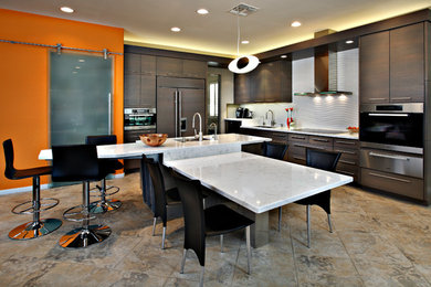 Large trendy l-shaped ceramic tile and brown floor eat-in kitchen photo in Phoenix with flat-panel cabinets, dark wood cabinets, white backsplash, paneled appliances, an undermount sink and an island