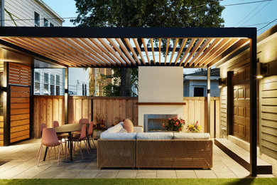 Esempio di un patio o portico minimalista dietro casa con un caminetto e una pergola