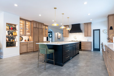 Open concept kitchen - large transitional l-shaped gray floor open concept kitchen idea in DC Metro with a single-bowl sink, shaker cabinets, brown cabinets, white backsplash, marble backsplash, black appliances and an island