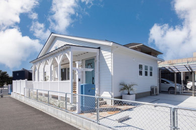 Ejemplo de fachada de casa blanca costera de una planta con revestimientos combinados y tejado a dos aguas