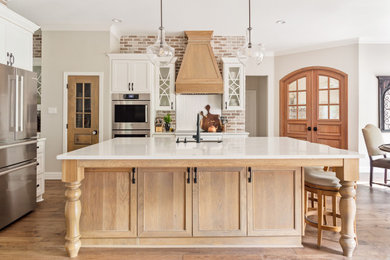 Example of a large transitional l-shaped medium tone wood floor and brown floor open concept kitchen design in Dallas with a farmhouse sink, recessed-panel cabinets, white cabinets, quartz countertops, red backsplash, brick backsplash, stainless steel appliances, an island and white countertops