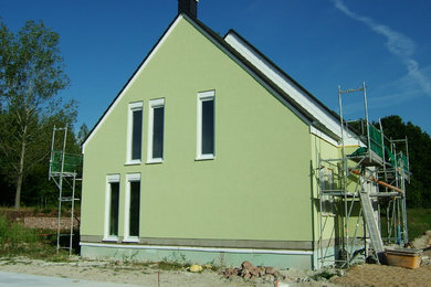 Mid-sized elegant green two-story stucco exterior home photo in Leipzig with a tile roof