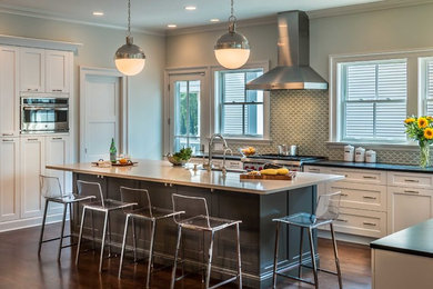 Example of a transitional l-shaped medium tone wood floor open concept kitchen design in Chicago with shaker cabinets, white cabinets, gray backsplash, an island, a farmhouse sink, cement tile backsplash and stainless steel appliances