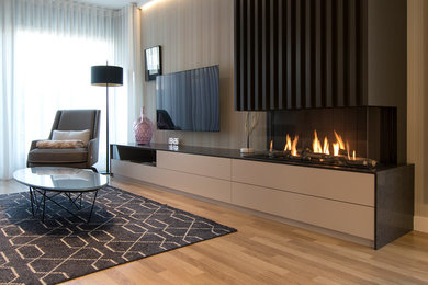 Diseño de salón abierto contemporáneo grande con paredes beige, suelo laminado, chimenea de esquina, marco de chimenea de metal, televisor colgado en la pared y suelo marrón