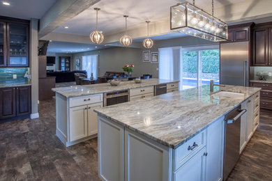 Large transitional l-shaped open plan kitchen in Miami with raised-panel cabinets, dark wood cabinets, granite benchtops, grey splashback, subway tile splashback, stainless steel appliances, dark hardwood floors, multiple islands, brown floor and a farmhouse sink.