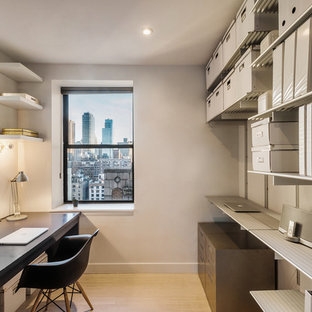 Design ideas for a small modern study in New York with white walls, bamboo flooring and a built-in desk.