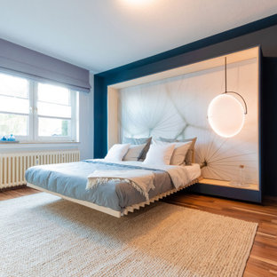 Mittelgroßes Modernes Hauptschlafzimmer mit blauer Wandfarbe, Laminat, braunem Boden, Tapetendecke und Tapetenwänden in Düsseldorf
