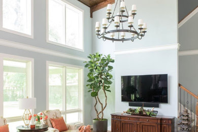 Diseño de salón abierto clásico renovado grande sin chimenea con paredes azules, suelo de madera en tonos medios, televisor colgado en la pared, suelo marrón y vigas vistas