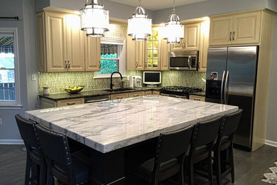 Example of a mid-sized transitional u-shaped dark wood floor and brown floor eat-in kitchen design in Philadelphia with marble countertops, an island, an undermount sink, raised-panel cabinets, beige cabinets, green backsplash, mosaic tile backsplash, stainless steel appliances and white countertops