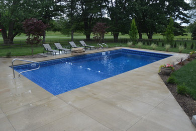 Esempio di una piscina chic rettangolare di medie dimensioni e dietro casa con fontane e lastre di cemento