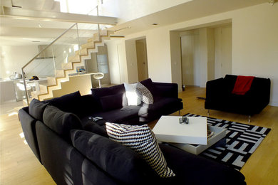 Modelo de sala de estar abierta contemporánea de tamaño medio sin chimenea con paredes blancas y suelo de madera clara